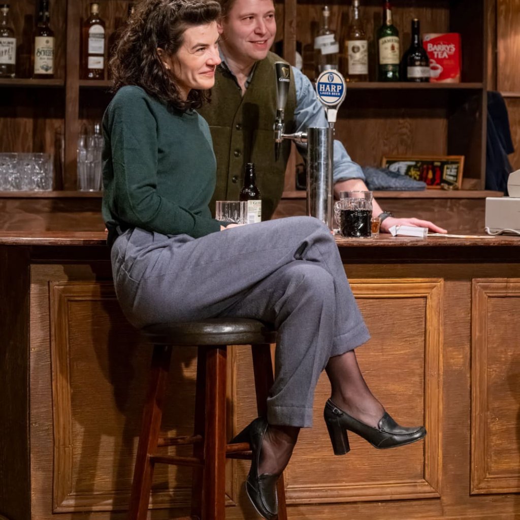 A woman sitting at a bar and the bartender standing behind her