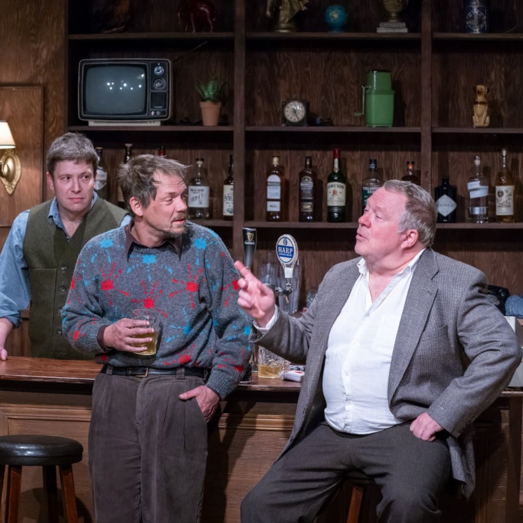 Three men in conversation at the bar in an Irish pub