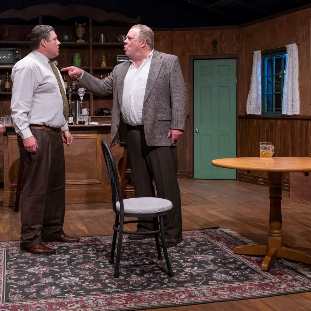 Two men in a heated discussion in an Irish pub. One of the men points angrily at the other.