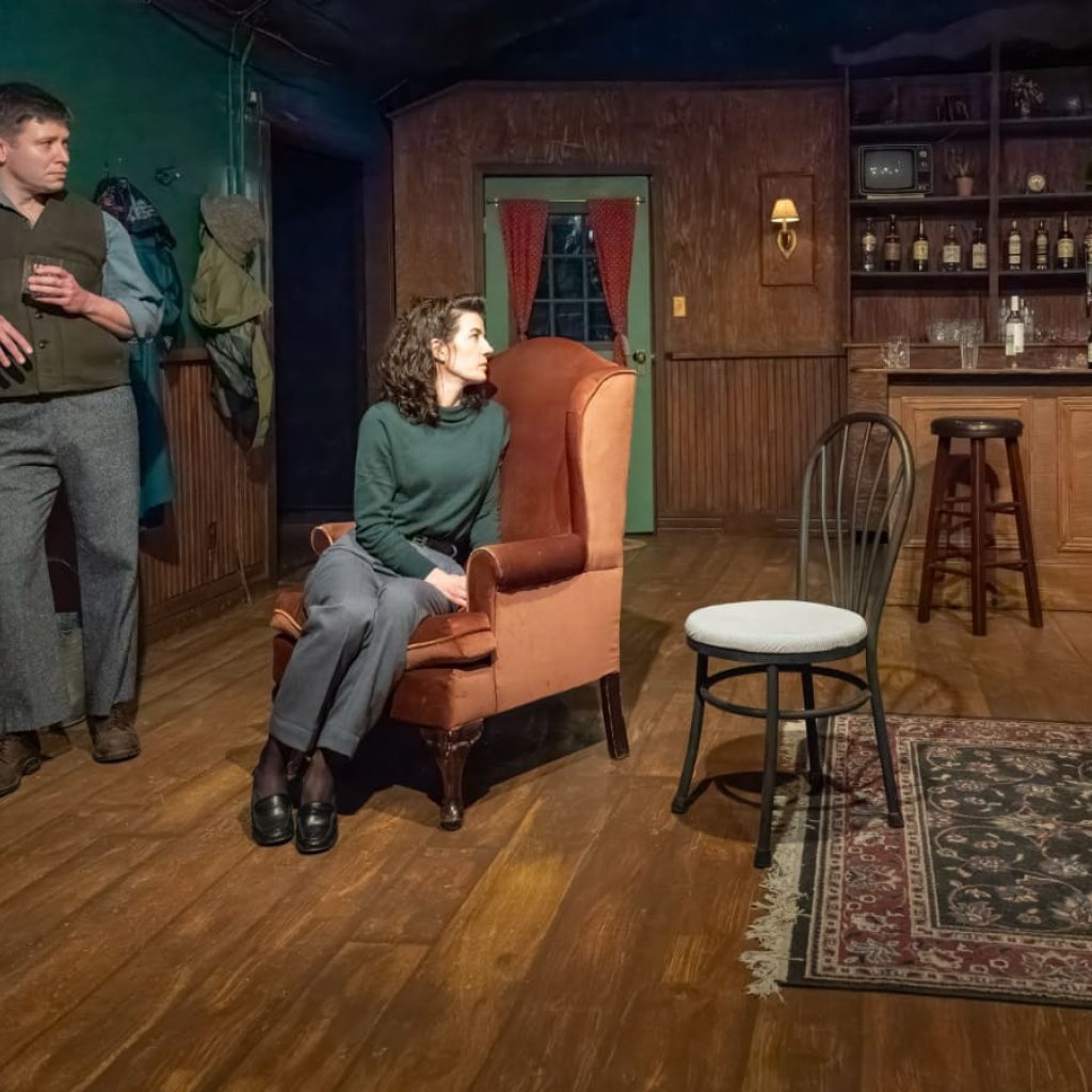Three people in a pub with a fireplace and armchair