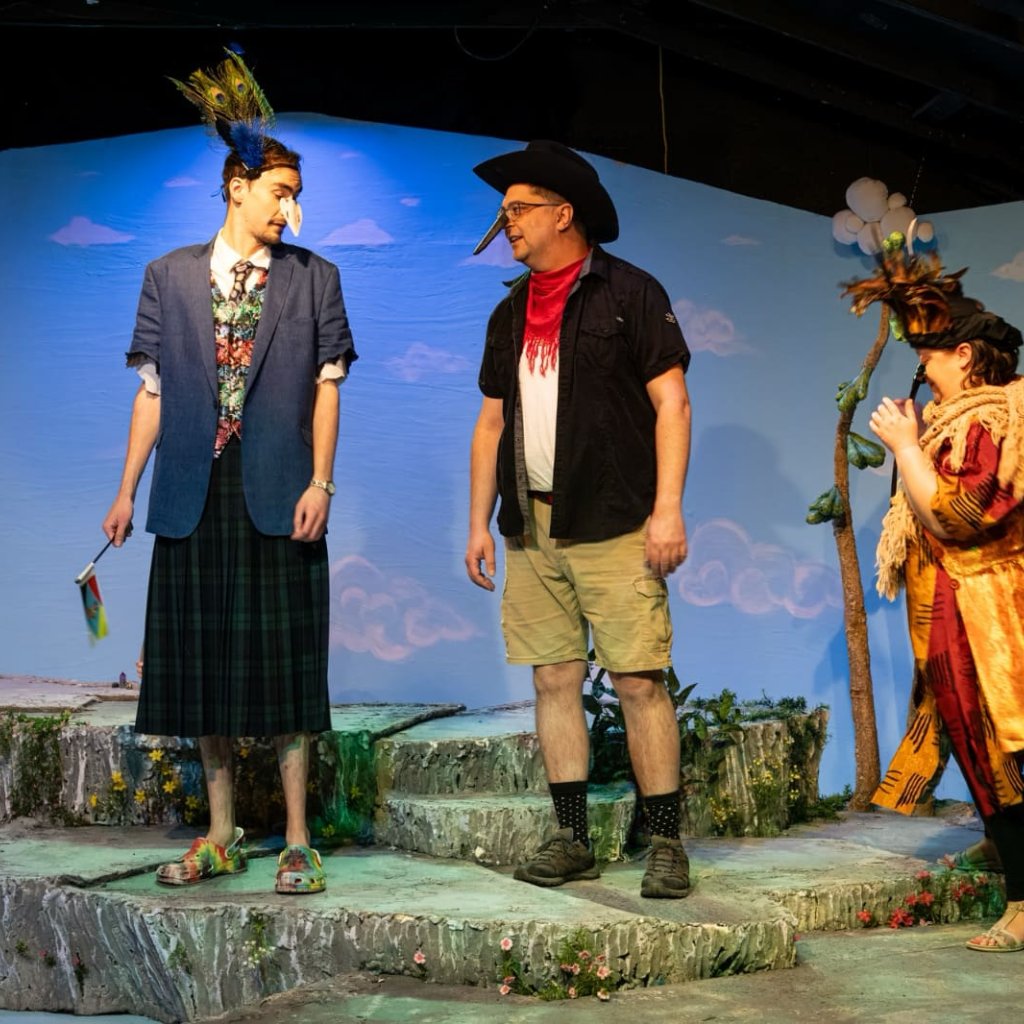 Two men in outrageous bird costumes talk while a woman dressed as a bird looks on