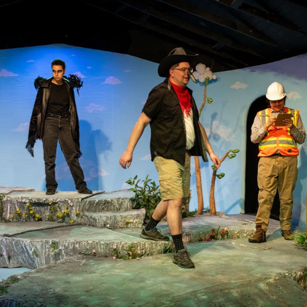 Three people dressed as birds look worried as a man dressed as a surveyor writes on a clipboard.