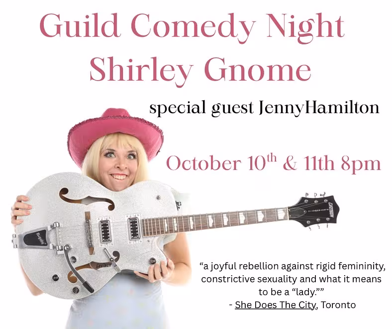 Guild Comedy Night Shirley Gnome. A woman wearing a pink cowboy hat holds up a white hollow-body electric guitar.